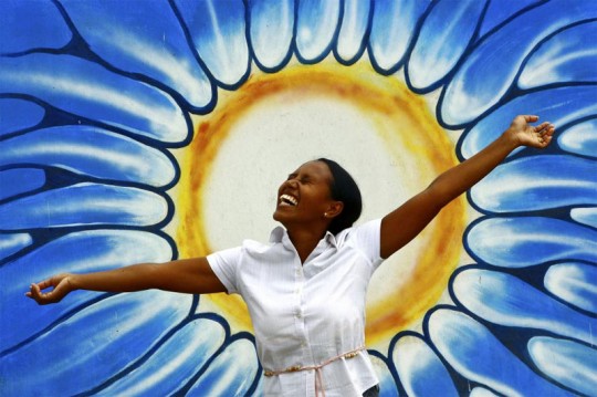 A woman poses in front of a graffiti representing the sun on the occasion of the observance of the World Mental Health Day.